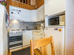 Cocina compacta con estufa, horno, microondas y un refrigerador pequeño.