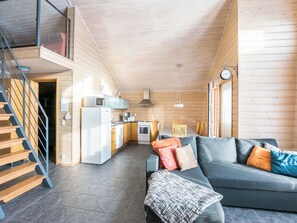A modern log cabin interior with a kitchen, dining area, and a staircase leading to an upper level. - Rinteenkotka mökki by Interhome (Hyrynsalmi)
