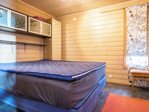 A room with a bed, a bench, and a window with a curtain. - Rinteenkotka mökki by Interhome (Hyrynsalmi)