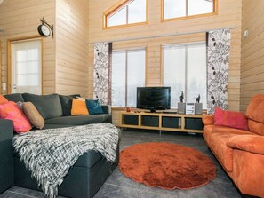 A modern living room with a sofa, a television, and decorative items. - Rinteenkotka mökki by Interhome (Hyrynsalmi)