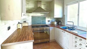 A kitchen with a stove, oven, and sink, wooden countertops, and white cabinets. - Villa - Sleeps 4 - Jacuzzi - Garden - Pet friendly (El Medano)