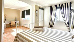 A bedroom with a large bed, a desk, a chair, and a window with curtains. - Villa - Sleeps 4 - Jacuzzi - Garden - Pet friendly (El Medano)