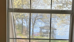 Una stanza con una grande finestra che si affaccia su un parco e un padiglione lungo un lago.