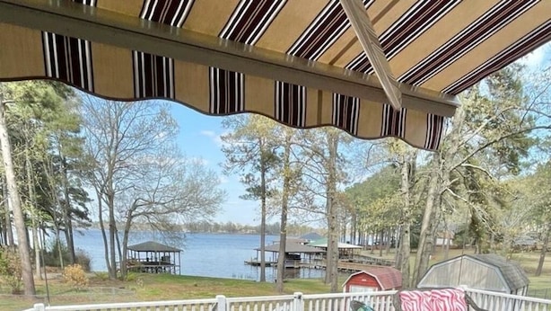 Una terrazza coperta con vista su un lago, un gazebo e un'area barbecue.