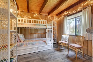 Cozy room with a bunk bed, ladder, and table, set amidst a serene outdoor view.