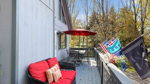 A covered outdoor seating area with a red sofa and a table with chairs, a red umbrella, and flags. - Spacious and Tranquil Lazy Lake Lodge Escape (Lake Ariel)