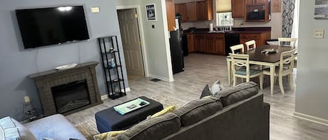 A living room with a fireplace, a television, a sofa, and a dining area with a table and chairs.
