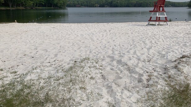 Una playa con una silla roja y un lago.