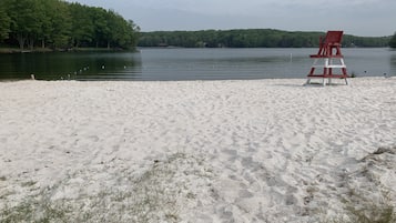 Une plage avec une chaise rouge et un lac.