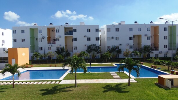 A modern apartment building with multiple balconies, a swimming pool, and well-maintained landscaping.