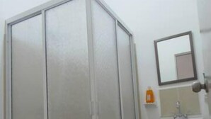 A bathroom with a toilet, a shower enclosure, a sink, and a mirror.