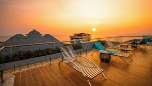 A rooftop terrace with sun loungers and a view of the sunset over the ocean. - Night Sea Hotel (Phu Quoc)