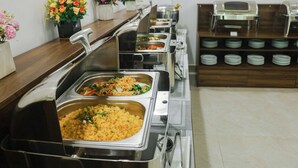 A buffet setup with various food stations and a row of flower vases. - Night Sea Hotel (Phu Quoc)