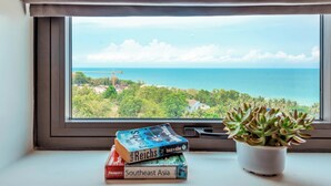 A window with a view of the sea and a plant on a windowsill. - Night Sea Hotel (Phu Quoc)