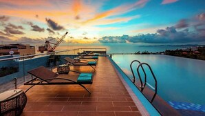 A rooftop infinity pool with lounge chairs and a view of the sunset over the ocean. - Night Sea Hotel (Phu Quoc)
