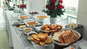 A buffet table with various food items, including bread, pastries, and a selection of beverages. - Night Sea Hotel (Phu Quoc)
