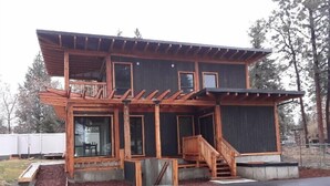 Une maison en bois à deux étages, dotée d’un balcon, de grandes fenêtres et d’un escalier menant à l’étage supérieur.