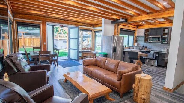 Un vaste espace de vie doté d’un plafond en bois, d’un canapé en cuir et d’une table basse.