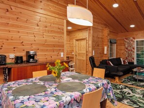 A wooden interior with a dining table set for four, a sofa, and a coffee station. - Kaitaranta by Interhome (Mikkeli)