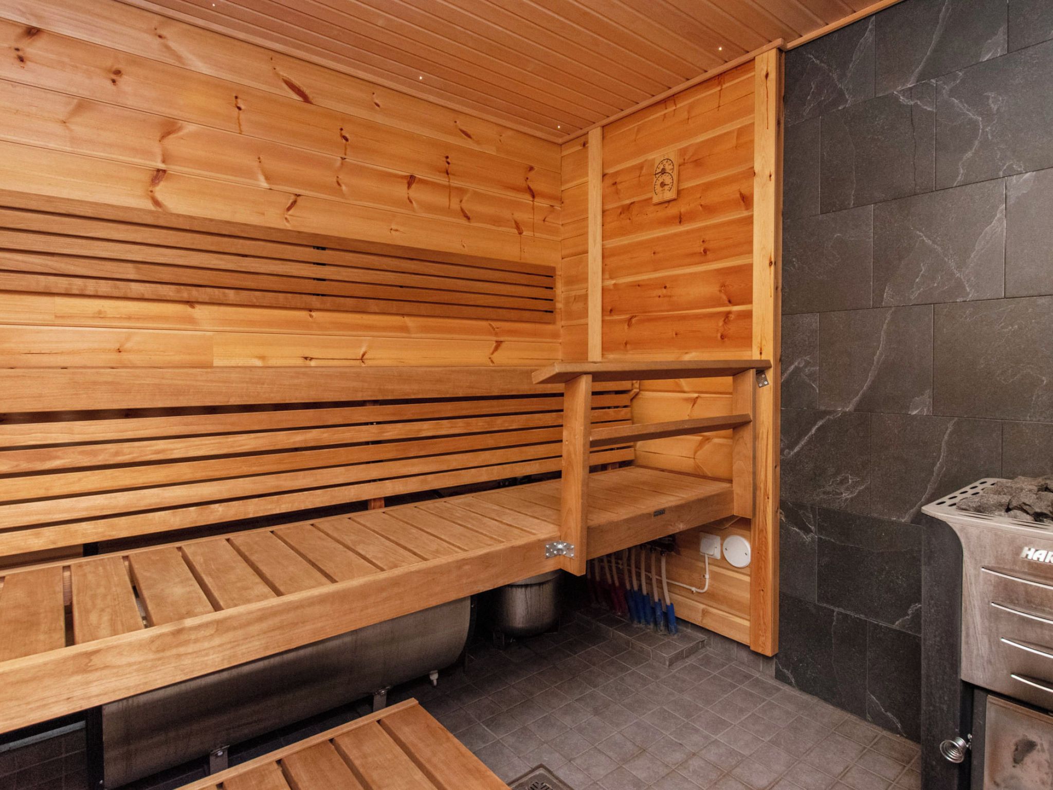 A sauna room with wooden benches and a stone wall.