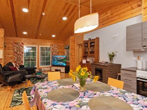 A cozy cabin interior with a dining area, a living room with a sofa and a TV, wooden walls, and a fireplace. - Kaitaranta by Interhome (Mikkeli)