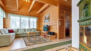 A cozy cabin interior with a wooden ceiling, a sofa, a TV, and a fireplace. - Lomataivas mökki by Interhome (Hyrynsalmi)