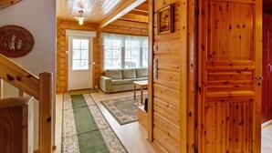 A wooden cabin interior with a staircase, a sofa, and a door. - Lomataivas mökki by Interhome (Hyrynsalmi)