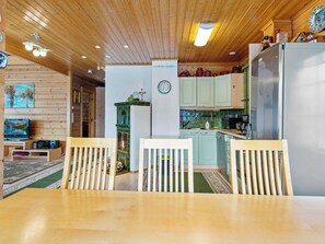 Un intérieur en bois comprenant un coin repas, une cuisine et un salon avec un téléviseur.