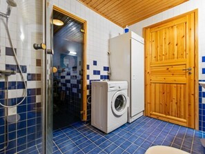 Bathroom features a glass-enclosed shower area, washing machine, and wooden door.