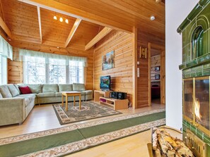 Un intérieur chaleureux de chalet en bois, avec un canapé, un téléviseur et une cheminée.