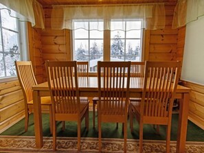 Enjoy meals in this cabin's dining area with a view of snow-covered trees.