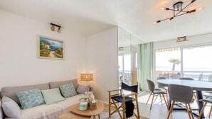 A modern living room with a sofa, a coffee table, and a dining area with chairs. - Le Palazzo del Mar by Interhome (Cavalaire)