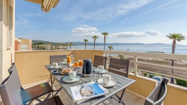 A balcony with a table set for breakfast, overlooking a scenic view of the sea and hills. - Le Palazzo del Mar by Interhome (Cavalaire)