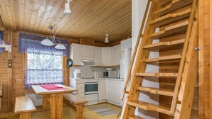 A wooden cabin interior with a kitchen, dining area, and a loft bed. - Lomaluola 5a paritalo by Interhome (Hyrynsalmi)