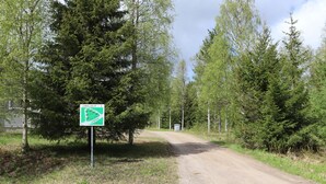 A dirt road leading through a forested area with a sign indicating a trail. - Lomaluola 5a paritalo by Interhome (Hyrynsalmi)