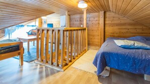 A cozy attic bedroom with a wooden ceiling, a bed, a desk, and a chair. - Lomaluola 5a paritalo by Interhome (Hyrynsalmi)