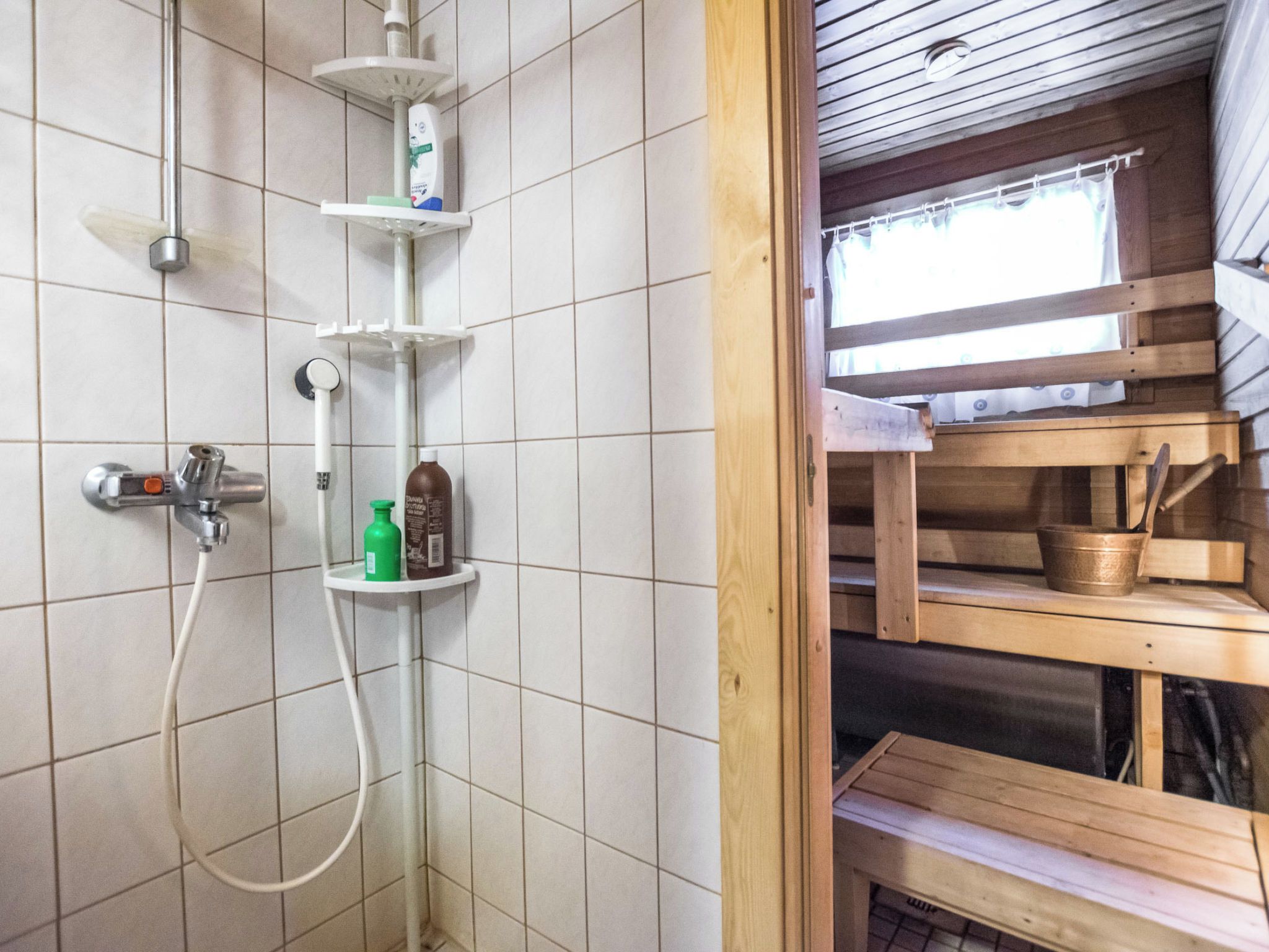 Un espace douche équipé d’un pommeau de douche à main, d’un robinet mural et d’une étagère pour les articles de toilette.