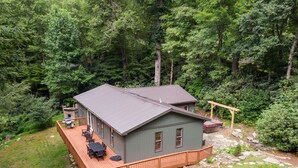 Una cabaña con terraza, rodeada de un bosque denso.