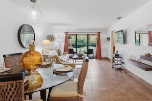 A dining area with a round table, wicker chairs, a large clock, and a view of the outdoors. - Saddlebrook Resort Condo | Golf Views | King Suite | Optional Resort Amenities (Wesley Chapel)