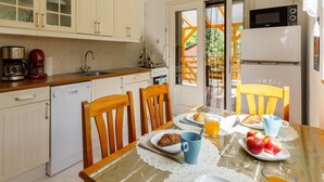 Une cuisine avec des meubles de rangement en bois, une table à manger avec des chaises, un réfrigérateur et un four à micro-ondes.