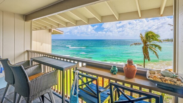 A balcony with wicker furniture, a table, and a view of the ocean. - "Oceanfront Condo: Coconut Tree & Ocean Views, Whale Watching, Paddlers, and Surfers at Wailua Bay!" (Kapaa)