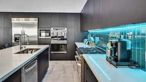 Een moderne keuken met een roestvrijstalen koelkast, een ingebouwde oven en een koffieapparaat.