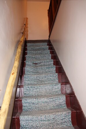 Staircase with a woven carpet and wooden steps, leading to an upper level.