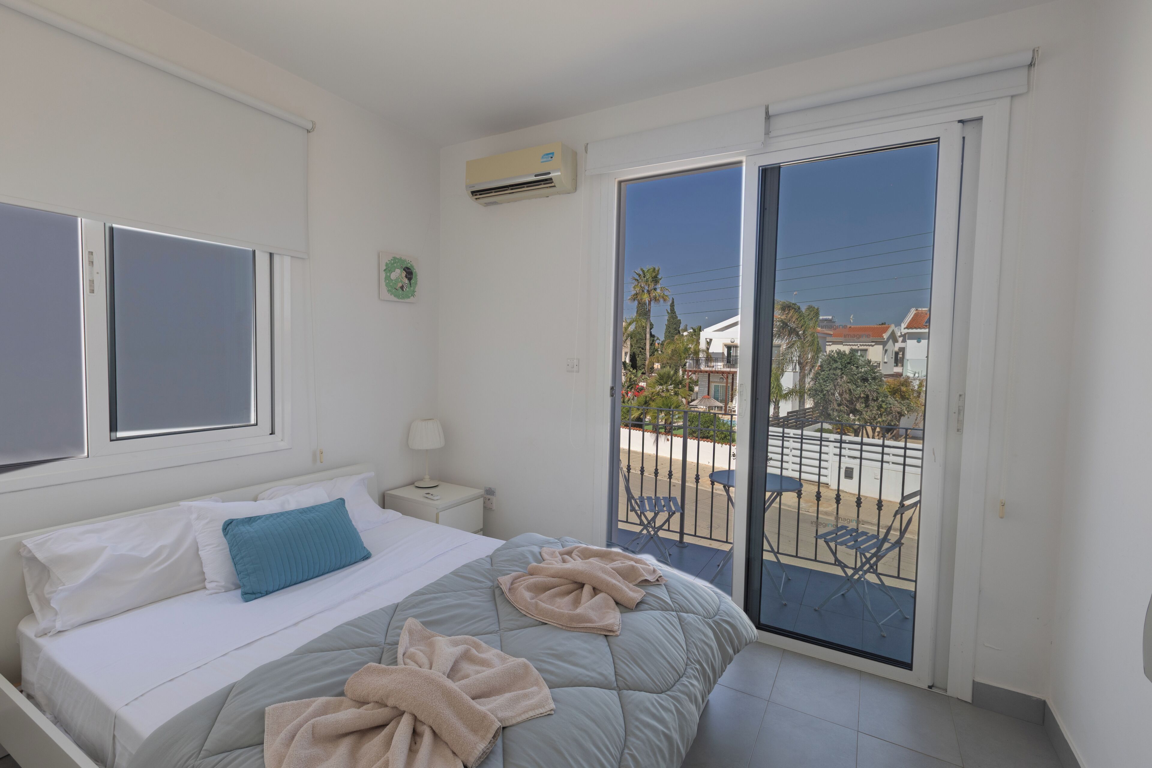 Une chambre à coucher avec un lit, une table de chevet, une fenêtre et un balcon avec des chaises.