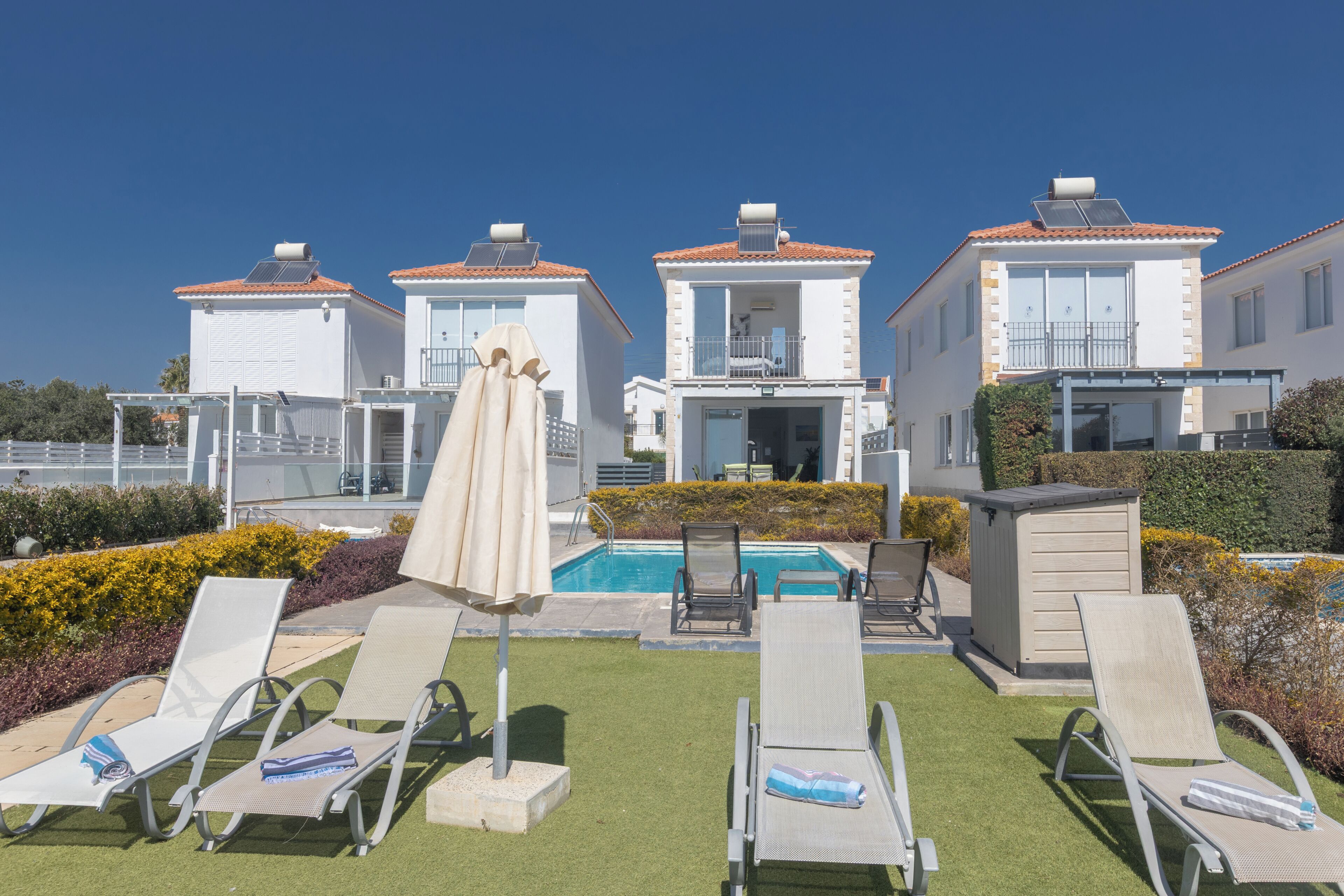 Un espace aménagé au bord de la piscine, avec des chaises longues, une petite piscine et un bâtiment doté d’un balcon.