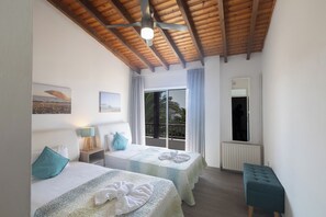 A hotel room with two beds, a ceiling fan, a window with curtains, a bench, and a radiator.
