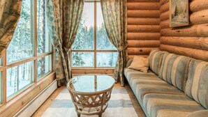 A log cabin interior with a sofa, a glass table, and curtains. - Sateenkaari mökki by Interhome (Hyrynsalmi)