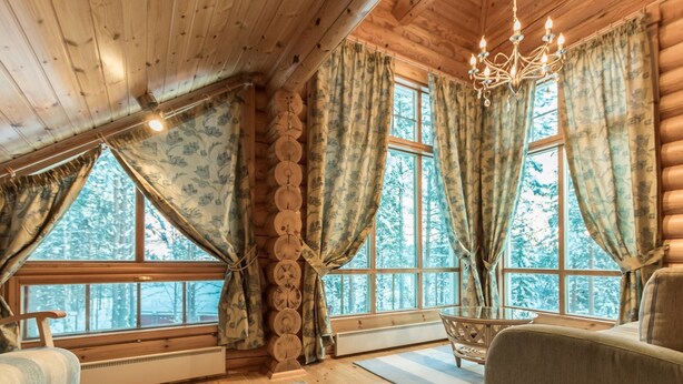 A log cabin interior with a cozy seating area, large windows, and a chandelier. - Sateenkaari mökki by Interhome (Hyrynsalmi)
