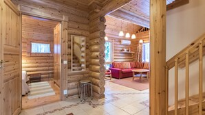 A log cabin interior with a wooden staircase, a sofa, and a dining table. - Sateenkaari mökki by Interhome (Hyrynsalmi)