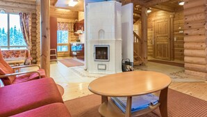 A log cabin interior with a fireplace, wooden walls, a sofa, and a dining table. - Sateenkaari mökki by Interhome (Hyrynsalmi)